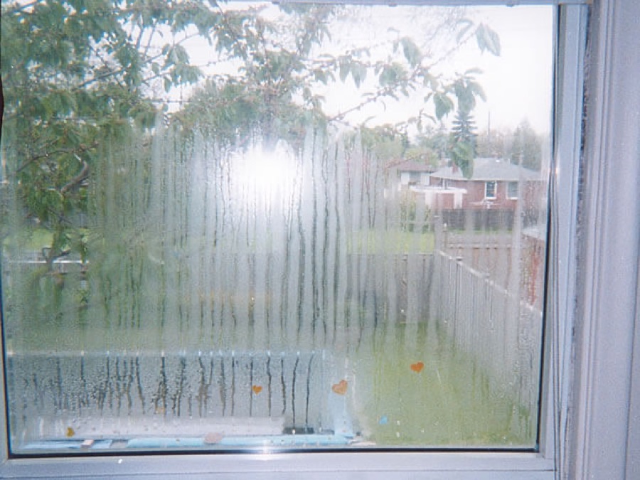 Cloudy double-pane window with condensation streaking down the inside of the glass