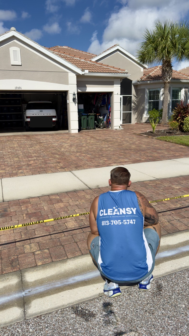 Cleansy technician checking the edge of a freshly sealed paver driveway for even coverage