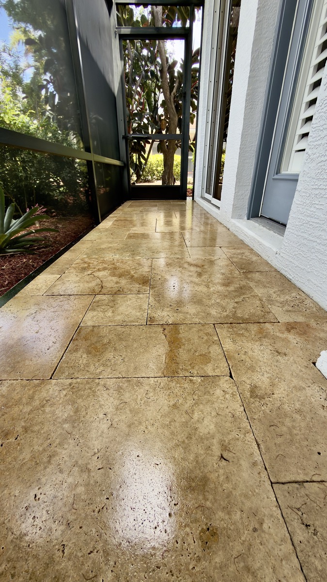 Sealed travertine walkway leading toward a screened lanai entrance