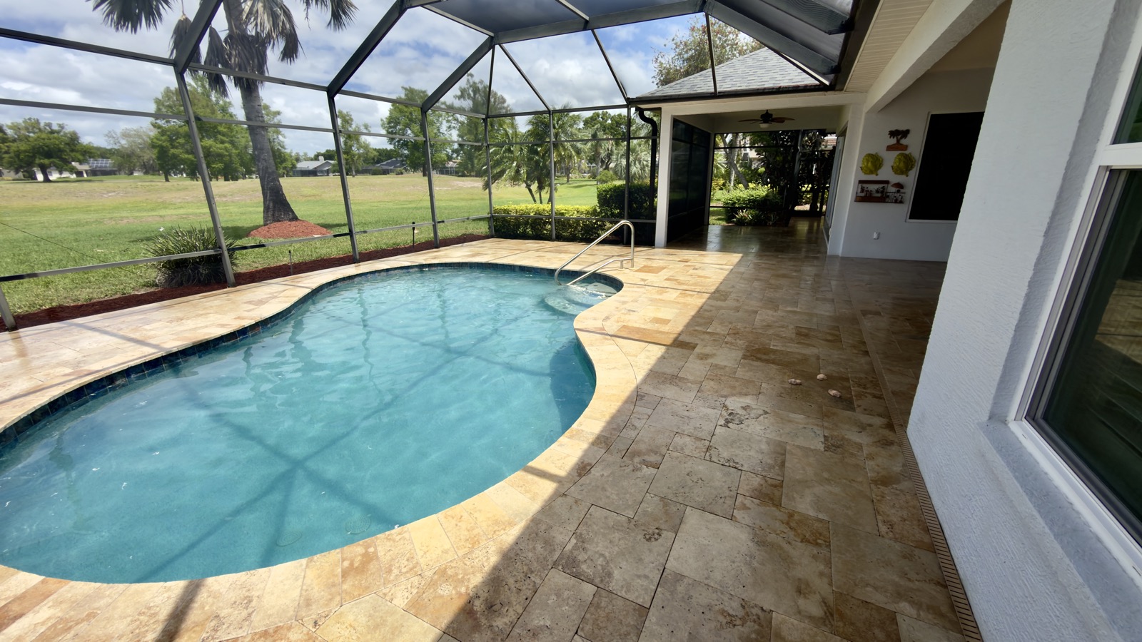 Sealed travertine pool deck and lanai with a wet-look sheen on a screened Parrish, FL patio