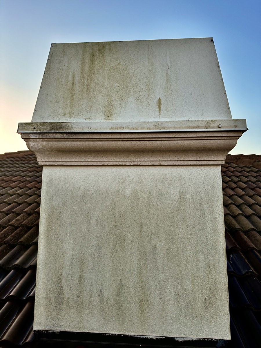 Chimney cap with dark algae streaking before a soft wash cleaning