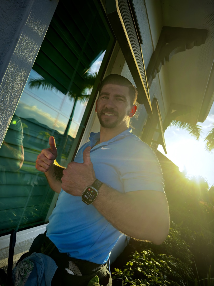 Cleansy team member giving a thumbs up beside a freshly cleaned window in the evening sun