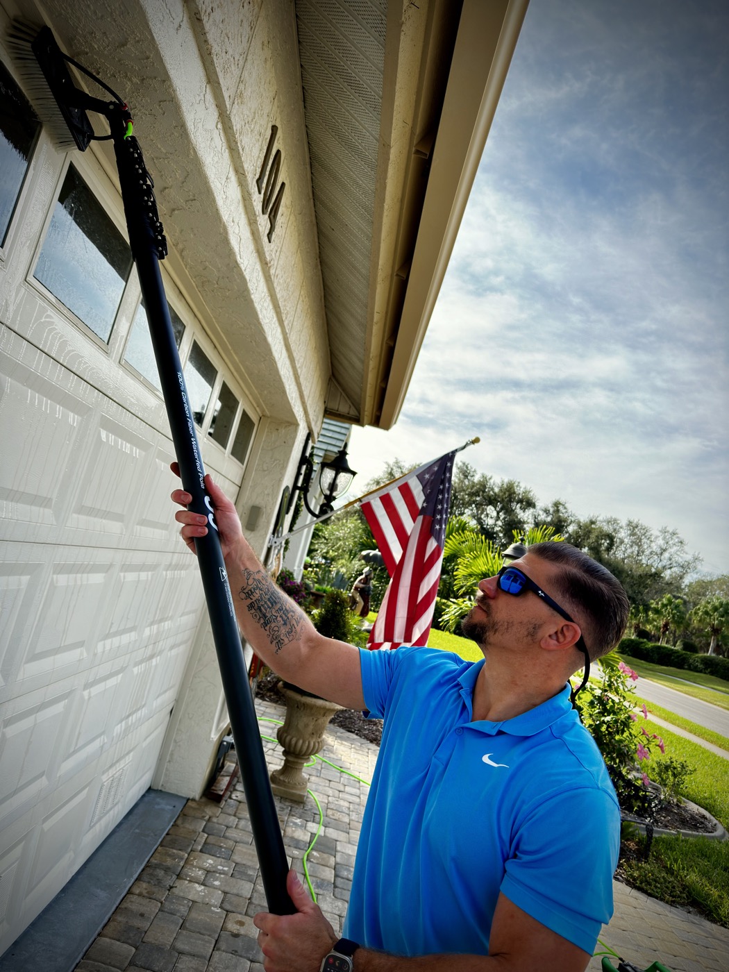 Cleansy technician using a carbon fiber water-fed pole with a brush to clean high windows on a Florida home