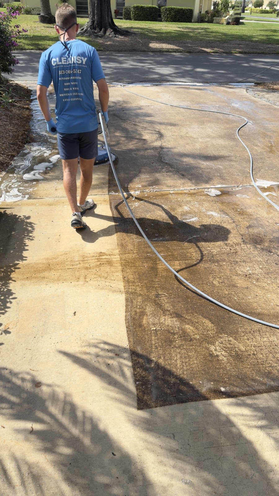 Driveway half pressure washed, showing a sharp line between the dirty and cleaned concrete