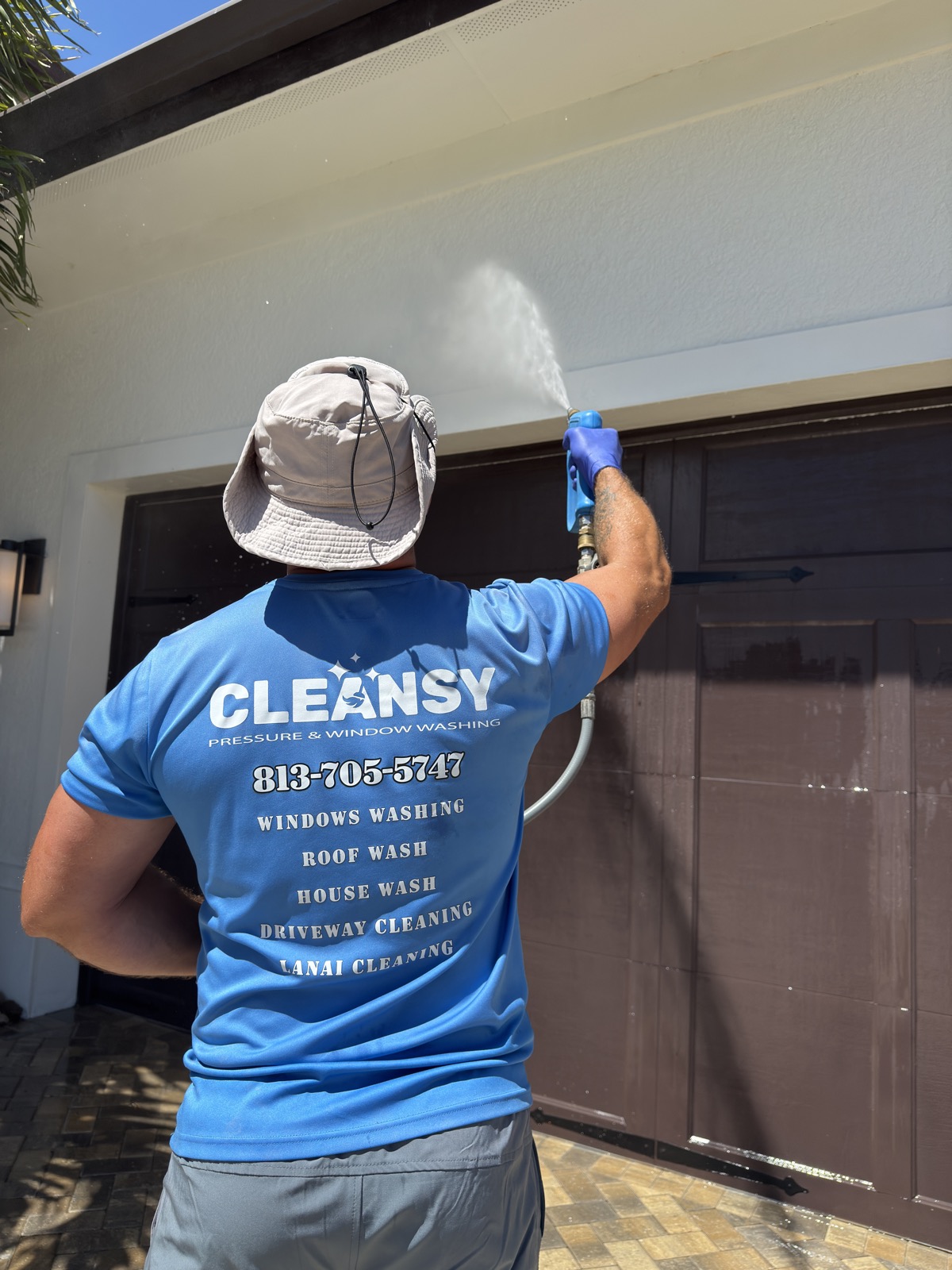 Cleansy technician soft washing a garage door and exterior siding