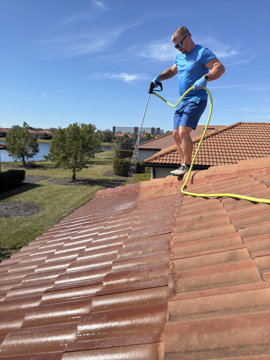 Cleansy technician soft washing a tile roof with a low-pressure wand