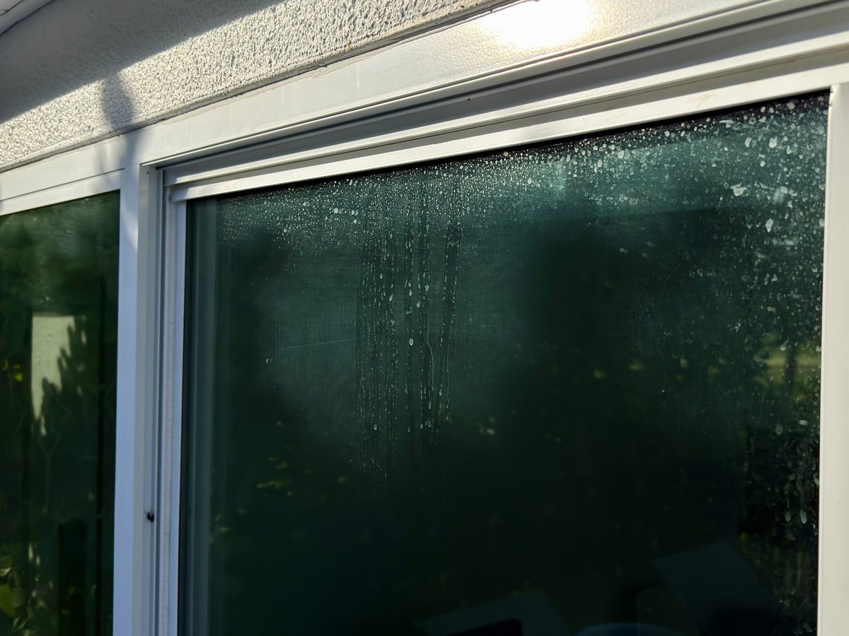 Sliding window covered in dried water spots and mineral film before cleaning