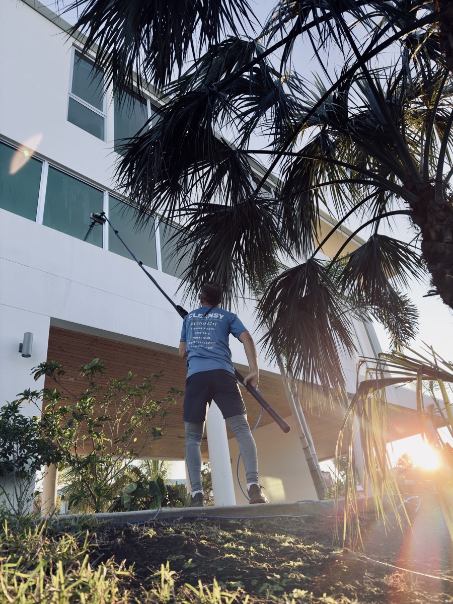 Cleansy technician using a water-fed pole to clean a high second-story window