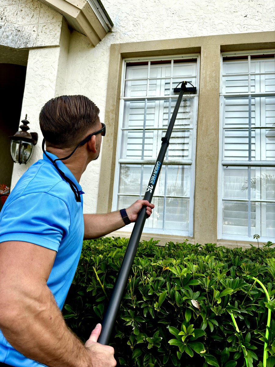 Cleansy technician cleaning exterior windows with a water-fed pole on a Sarasota home