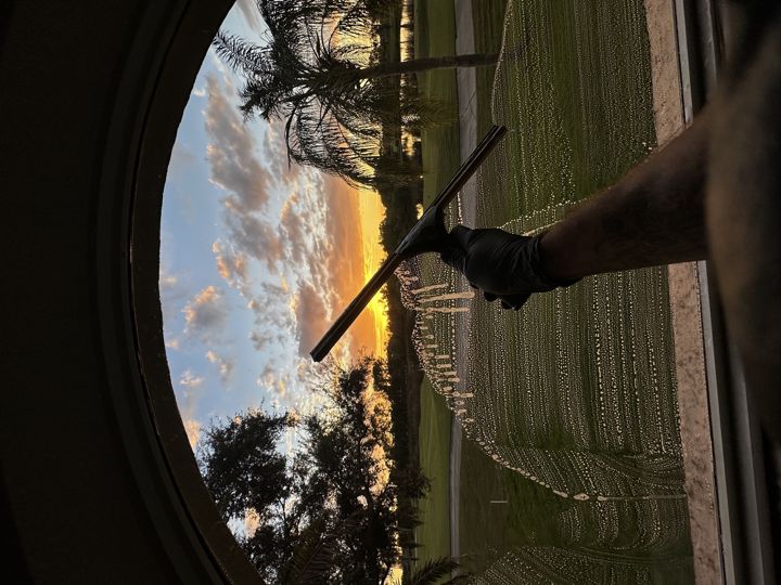 Hand squeegee finish on exterior window glass at sunset
